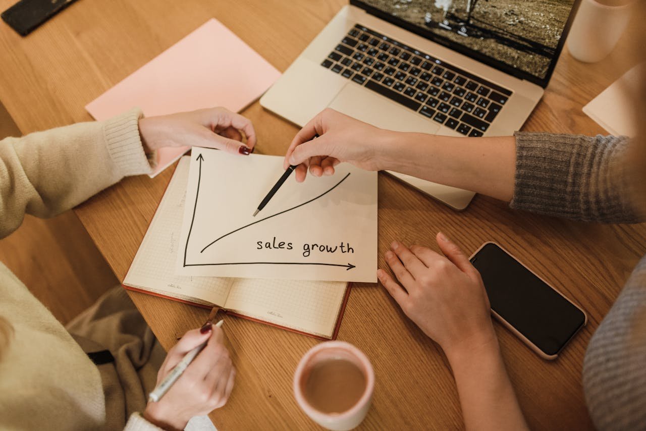 Offerings Two women plan sales growth with graphs and technology in an office setting.