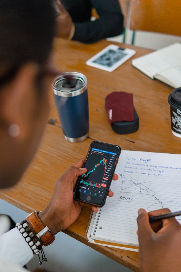 Offerings A person reviewing stock market data on a smartphone while taking notes during a meeting.